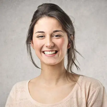 Close-up of a smiling woman with a light pink shirt, with a soft background.